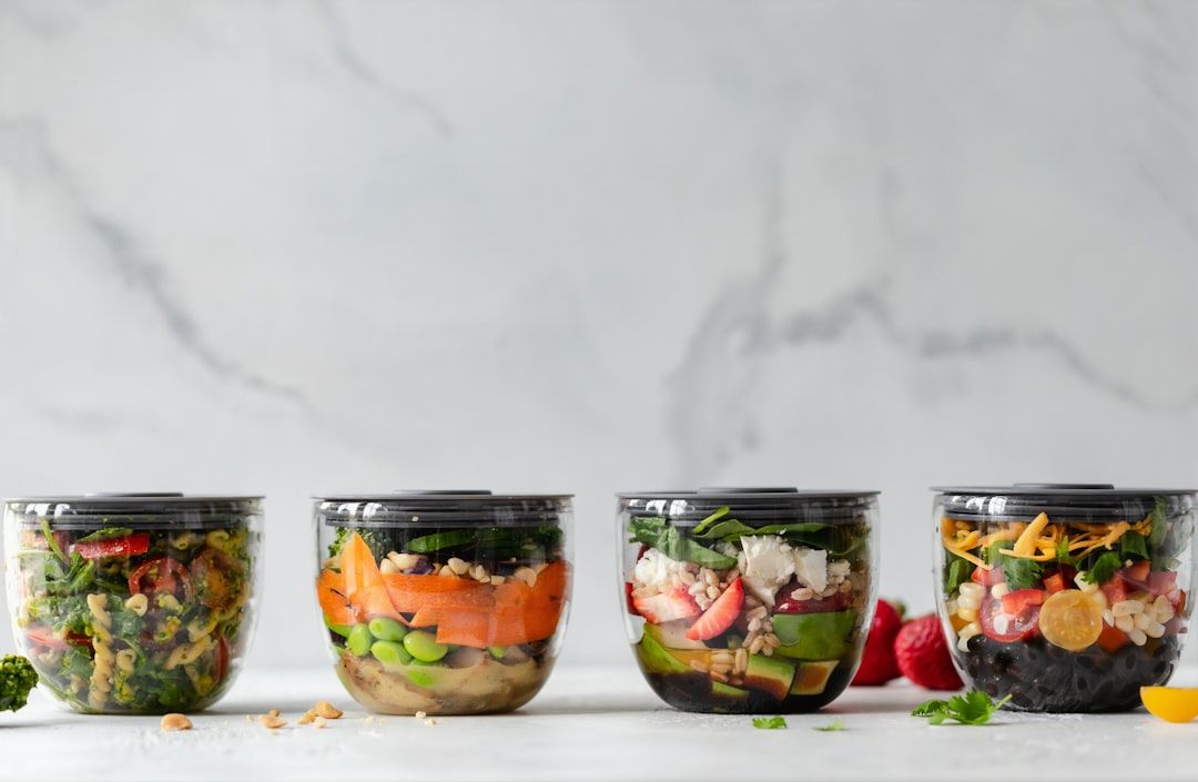 Fyra genomskinliga skålar fyllda med färgglada och näringsrika sallader för meal prep.